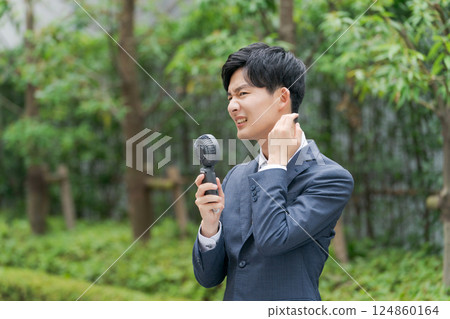 A young office worker with a handheld fan A young office worker with a handheld fan 124860164