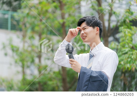 夏季商人拿著一把方便的風扇 夏季商人拿著一把方便的風扇 124860203