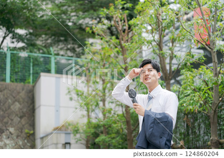 Summer businessman holding a handy fan Summer businessman holding a handy fan 124860204