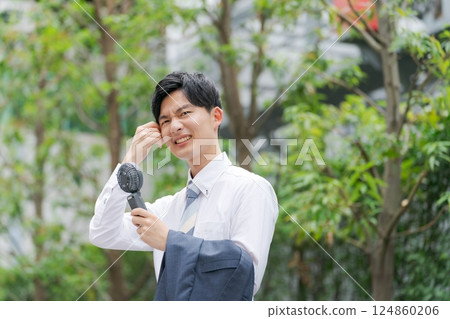 夏季商人拿著一把方便的風扇 夏季商人拿著一把方便的風扇 124860206