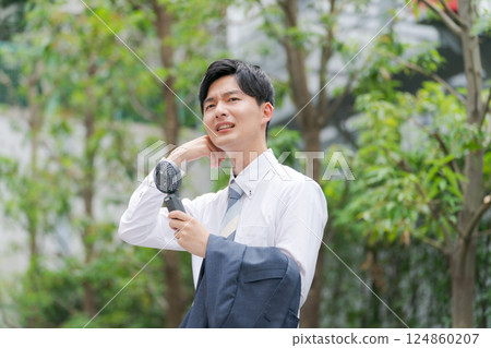 夏季商人拿著一把方便的風扇 夏季商人拿著一把方便的風扇 124860207