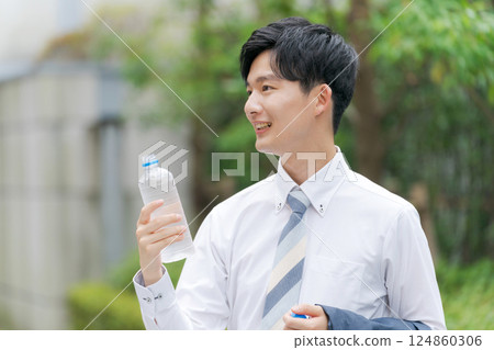 Office worker drinking water in the park 124860306