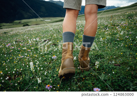 Hiker legs walking on beautiful flowering grassland Hiker legs walking on beautiful flowering grassland 124863000