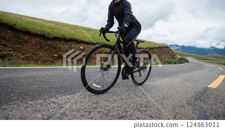 Riding bike on grassland mountain top trail 124863011