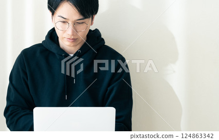 Man using a computer by the wall Man using a computer by the wall 124863342