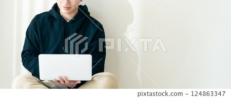 Man using a computer by the wall Man using a computer by the wall 124863347