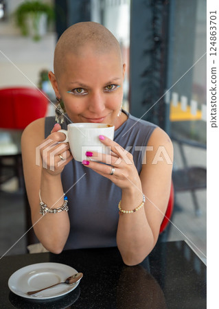 Confident young woman with cancer enjoying coffee in a cafe, embracing life despite illness. The concept shows that a cancer diagnosis does not take away the ability to enjoy normal activities 124863701
