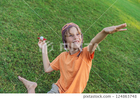 Boy wearing a pilot hat running through the grass with a toy airplane, dreaming of adventures. Childhood, imagination, and freedom concept Boy wearing a pilot hat running through the grass with a toy airplane, dreaming of adventures. Childhood, imagination, and freedom concept 124863748
