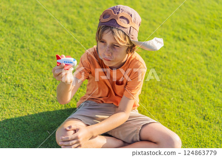 Boy wearing a pilot hat running through the grass with a toy airplane, dreaming of adventures. Childhood, imagination, and freedom concept Boy wearing a pilot hat running through the grass with a toy airplane, dreaming of adventures. Childhood, imagination, and freedom concept 124863779