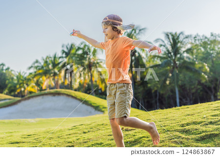 Boy wearing a pilot hat running through the grass with a toy airplane, dreaming of adventures. Childhood, imagination, and freedom concept Boy wearing a pilot hat running through the grass with a toy airplane, dreaming of adventures. Childhood, imagination, and freedom concept 124863867