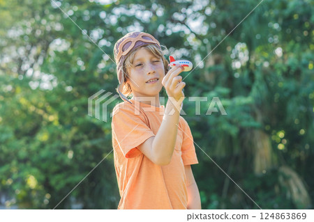 Boy wearing a pilot hat running through the grass with a toy airplane, dreaming of adventures. Childhood, imagination, and freedom concept Boy wearing a pilot hat running through the grass with a toy airplane, dreaming of adventures. Childhood, imagination, and freedom concept 124863869