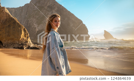 Smiling woman in denim shirt standing on beach Smiling woman in denim shirt standing on beach 124864639