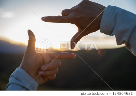 Hands in a frame shape against sunset sky Hands in a frame shape against sunset sky 124864681
