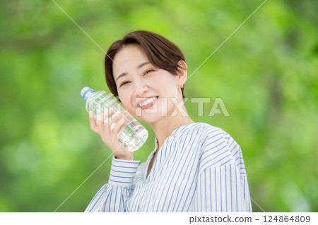 Woman holding a plastic bottle, hydration, fresh greenery Woman holding a plastic bottle, hydration, fresh greenery 124864809