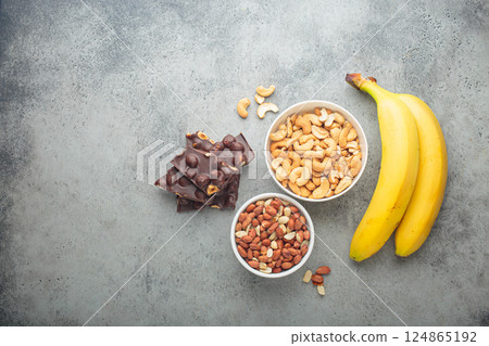 Cashews, peanuts, bananas and chocolate with hazelnuts representing magnesium rich food top view 124865192