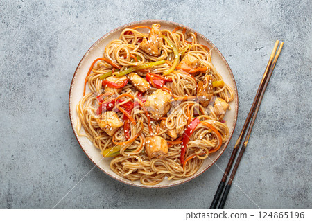 Udon noodles stir fry with chicken and vegetables sprinkled with sesame seeds top view Udon noodles stir fry with chicken and vegetables sprinkled with sesame seeds top view 124865196