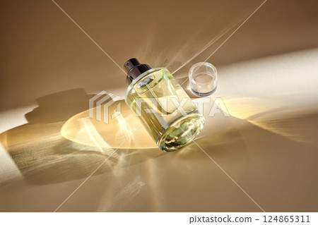Perfume on a beige background in the rays of bright sun with beautiful highlights. Perfume on a beige background in the rays of bright sun with beautiful highlights. 124865311