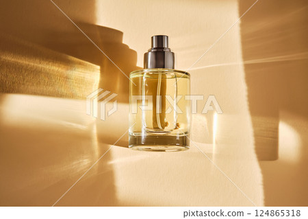 Perfume on a beige background in the rays of bright sun with beautiful highlights. Perfume on a beige background in the rays of bright sun with beautiful highlights. 124865318