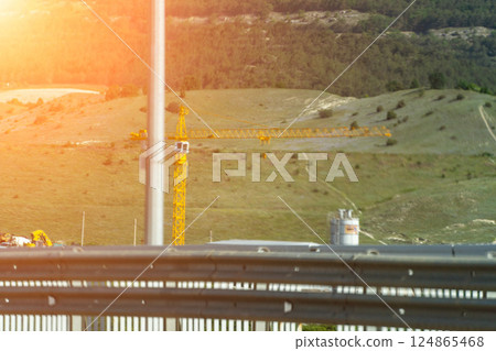 Bridge Construction, Aerial View, Sunset: High-angle daytime shot showing bridge construction progress in hilly landscape. Bridge Construction, Aerial View, Sunset: High-angle daytime shot showing bridge construction progress in hilly landscape. 124865468