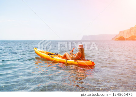 Kayak sea woman. Happy attractive woman with long hair in red swimsuit, swimming on kayak. Summer holiday vacation and travel concept. 124865475
