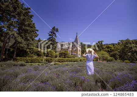 A woman is walking through a field of purple flowers 124865483