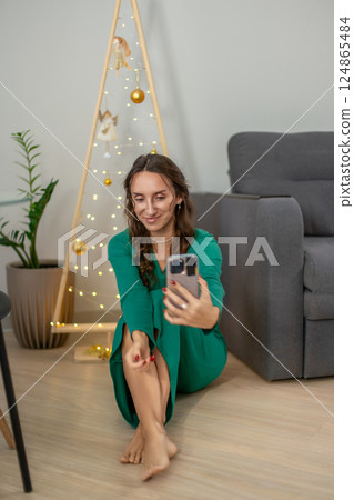 Woman Christmas Selfie Phone: Indoor holiday video call, December, festive mood. 124865484