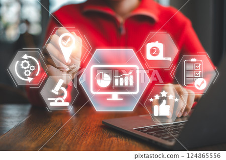 A person interacts with a digital interface displaying data analytics and monitoring tools on a laptop in a contemporary setting. 124865556