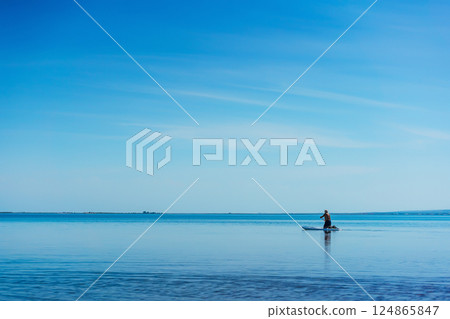man paddle boarding on lake. boy learning to swim on air board man paddle boarding on lake. boy learning to swim on air board 124865847