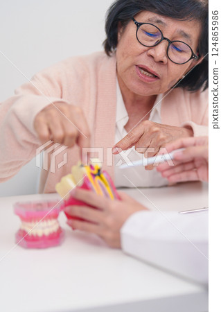 Elderly Patient consulting Dentist to Tooth disease, Senior Health Medical Diagnosis. Anatomy teeth model for Oral Teeth decay, Scrape off tartar. March Oral health, Dentist Day, False Teeth concept 124865986