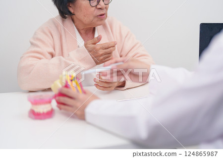 Elderly Patient consulting Dentist to Tooth disease, Senior Health Medical Diagnosis. Anatomy teeth model for Oral Teeth decay, Scrape off tartar. March Oral health, Dentist Day, False Teeth concept 124865987