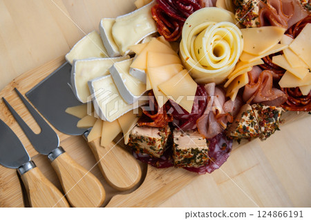 Food trend gift aperitivo party idea. Appetizers wooden grazing board with different antipasti charcuterie snacks and cheese. Assorted cheese meat platter. Disordered eating 124866191