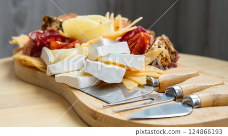 Wooden charcuterie cheese board holiday present idea. Snack starter plate for dinner with wine. Italian appetizers or antipasto set with gourmet food. Buffet party Wooden charcuterie cheese board holiday present idea. Snack starter plate for dinner with wine. Italian appetizers or antipasto set with gourmet food. Buffet party 124866193