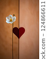 A pristine white flower is elegantly standing next to a bright red heart 124866611