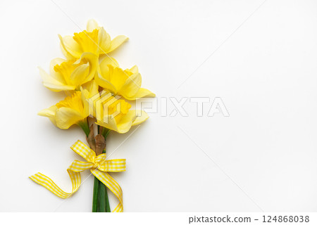 Yellow daffodils with ribbon bow lying on white background Yellow daffodils with ribbon bow lying on white background 124868038
