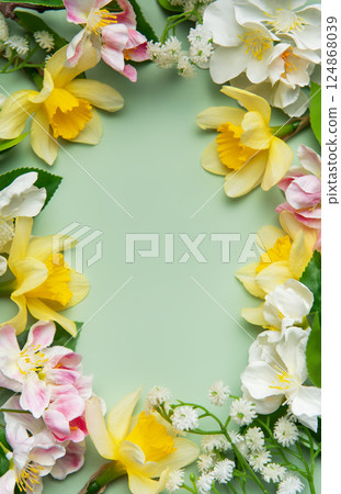 Daffodils and apple blossoms creating a floral frame on green background Daffodils and apple blossoms creating a floral frame on green background 124868039