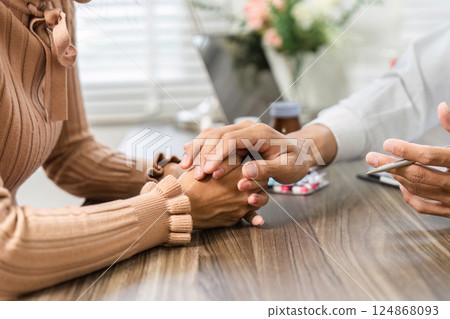 Compassionate Health Consultation and Emotional Support. Doctor holding a patient's hand during a consultation. 124868093