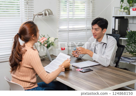 Patient Care and Medication Review. A doctor discussing health plans with a female patient in a clinical setting. 124868150