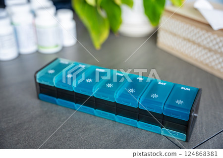 Weekly pill organizer with labeled compartments for daily medication doses. Concept of health management and medication planning Weekly pill organizer with labeled compartments for daily medication doses. Concept of health management and medication planning 124868381
