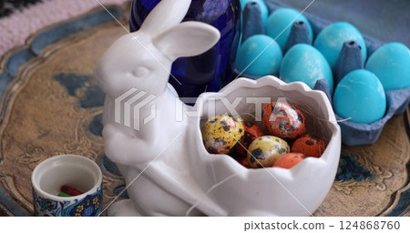 Colorful Easter eggs and quail eggs arranged in a festive Easter Bunny shaped bowl on a decorative plate Colorful Easter eggs and quail eggs arranged in a festive Easter Bunny shaped bowl on a decorative plate 124868760