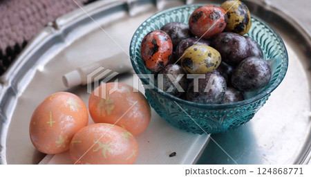 Easter eggs and quail eggs beautifully decorated with pearl accents sitting in a vintage bowl surrounded by colorful designs perfect for a festive celebration 124868771