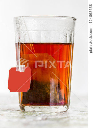 Faceted glass of boiled water and tea bag 124868888
