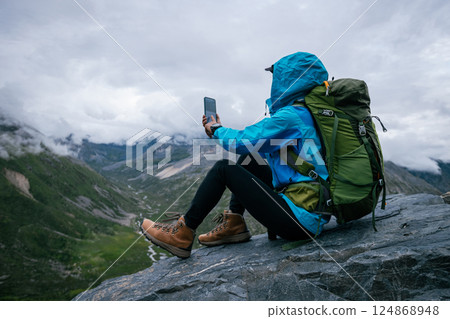 Hiking woman taking photo with smart phone on high altitude mountain top Hiking woman taking photo with smart phone on high altitude mountain top 124868948