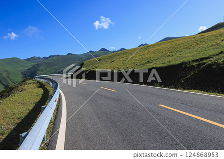 Asphalt road on flowering grassland mountain top 124868953