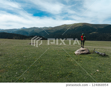 Aerial view of woman cyclist with mountain bike on flowering grassland mountain 124868954