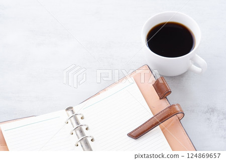 An image of working at a desk with a ring-type notebook open while drinking freshly brewed coffee. 124869657