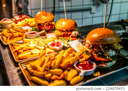 Home made hamburger with lettuce, cheese, beef meat and french fries placed on stainless steel table Home made hamburger with lettuce, cheese, beef meat and french fries placed on stainless steel table 124870451