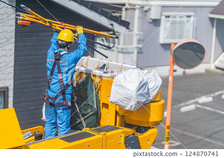 A maintenance worker prepares a work platform to remove a crow's nest from a utility pole. 124870741