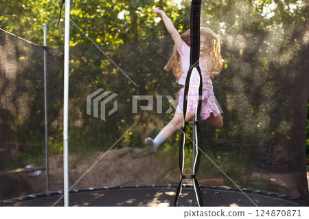Child girl jumping on big trampoline outdoors Child girl jumping on big trampoline outdoors 124870871