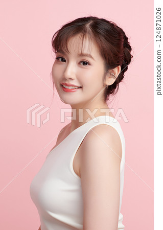 A beautiful young Asian woman with clean, fresh skin against a pink background. Skincare, facial treatment, cosmetology, beauty, and spa. An elegant portrait of an Asian woman. 124871026