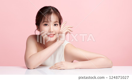 A beautiful young Asian woman with clean, fresh skin against a pink background. Skincare, facial treatment, cosmetology, beauty, and spa. An elegant portrait of an Asian woman. 124871027